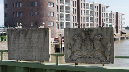 Gedenktafel Schleuse Neuer Hafen M6459 (c) Helmut Gross_Erlebnis Bremerhaven_WEB.jpg Zwei steinerne Gedenktafeln mit Inschrift und Löwenwappen vor einem Hafenbecken.