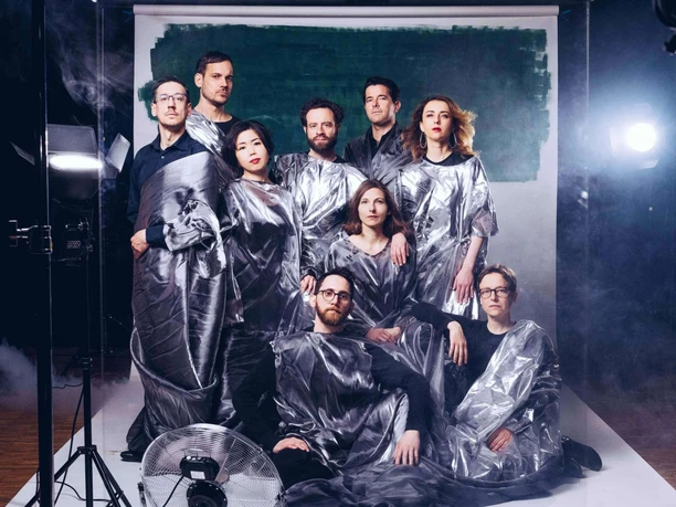 Ensemble Garage Group in silvery robes poses in the studio in front of a dark background