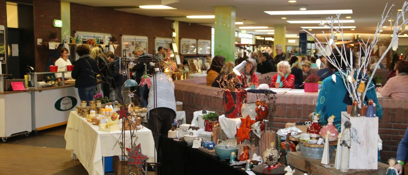 Hobby&Freizeit-2.JPG Leute schlendern entlang dekorativer Stände mit Handwerkskunst in einer gut besuchten Halle.