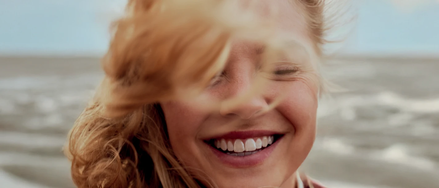 Frauenzeit Eine Frau steht im Watt, der Wind weht ihr durch die Haare