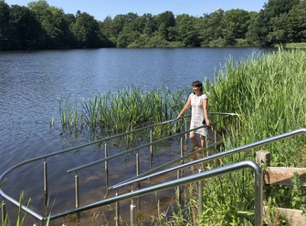 Speckenbütteler Park (c) Mailin Knoke (87)_WEB.jpg Eine Frau tritt lächelnd Wasser in die Kneipp-Anlage im Teich des Gesundheitsparks Speckenbüttel