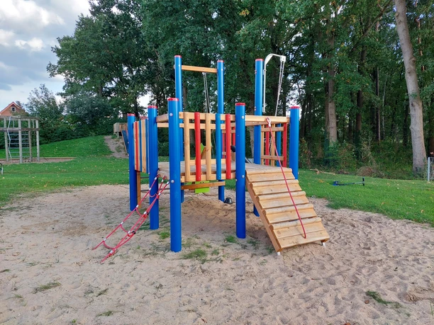 Elsa Brändström Straße Kletter- und Spielanlage mit Rampe und Seilen auf Sandfläche, umgeben von Bäumen