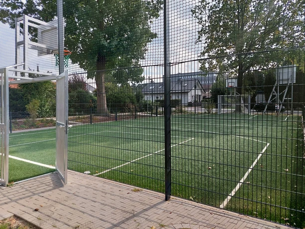 Soccer Court Eingezäunter Soccer Court mit Kunstrasen und Toren neben Spielplatz