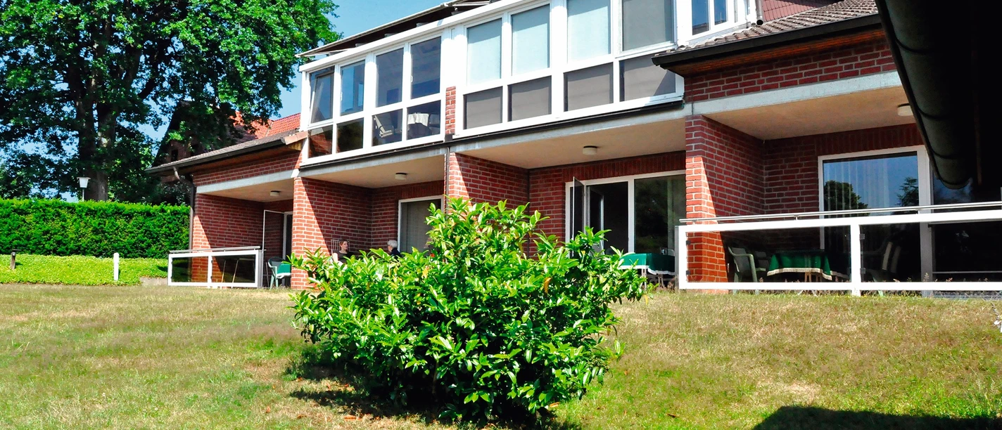 GERDA Wolter / Ferienwohnungen Außenansicht Außenansicht eines Backsteingebäudes mit Balkonen und einem Wintergarten, umgeben von einem Garten.