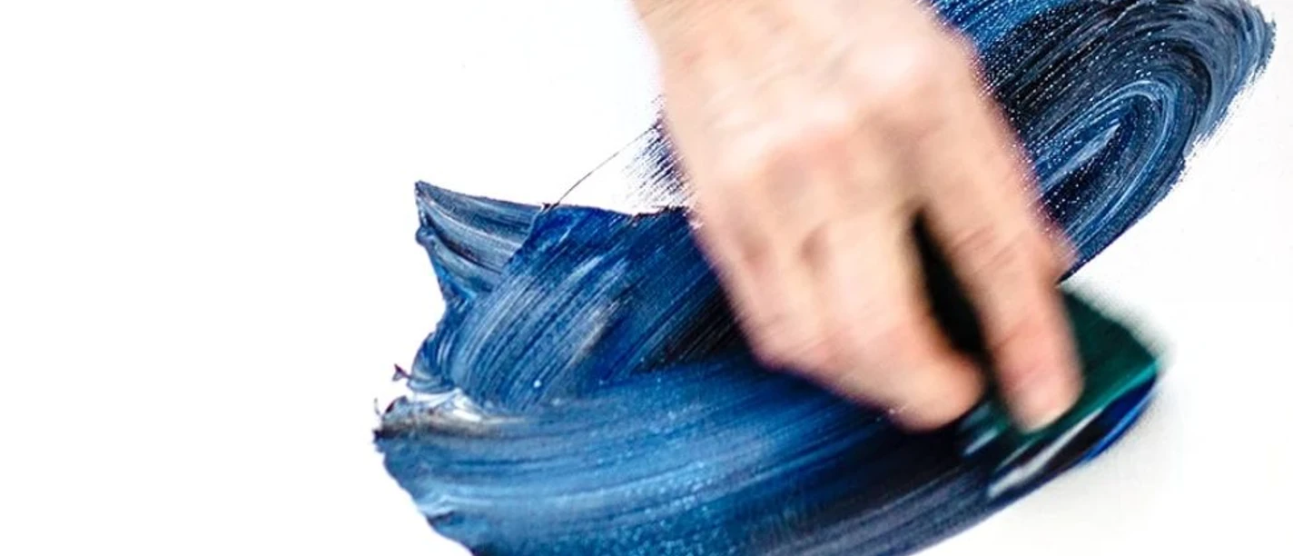 Tagträume_Maren Hoch (c) KuKuK.jpg Eine Hand malt mit Hilfe eines Schwammes mit blauer Farbe auf weißen Untergrund.