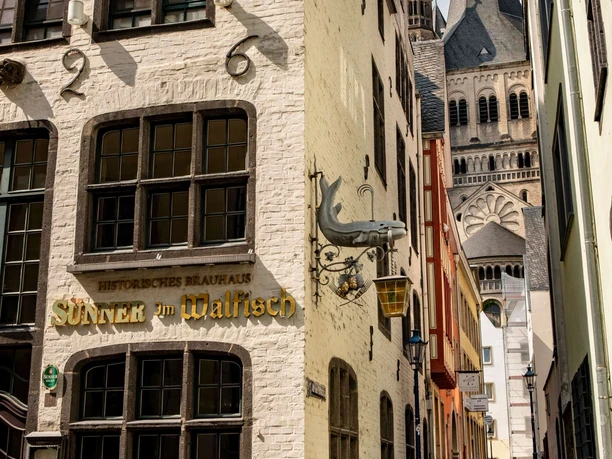 Old town of Cologne Narrow cobblestone alley with historic facades and a view of the tower of a large church.