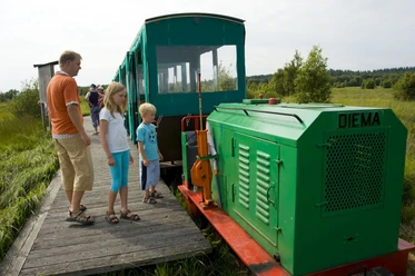 Moorbahn Ahlenmoor Familie auf einem Holzsteg entdeckt die grüne Moorbahn im sonnigen Ahlenmoor.