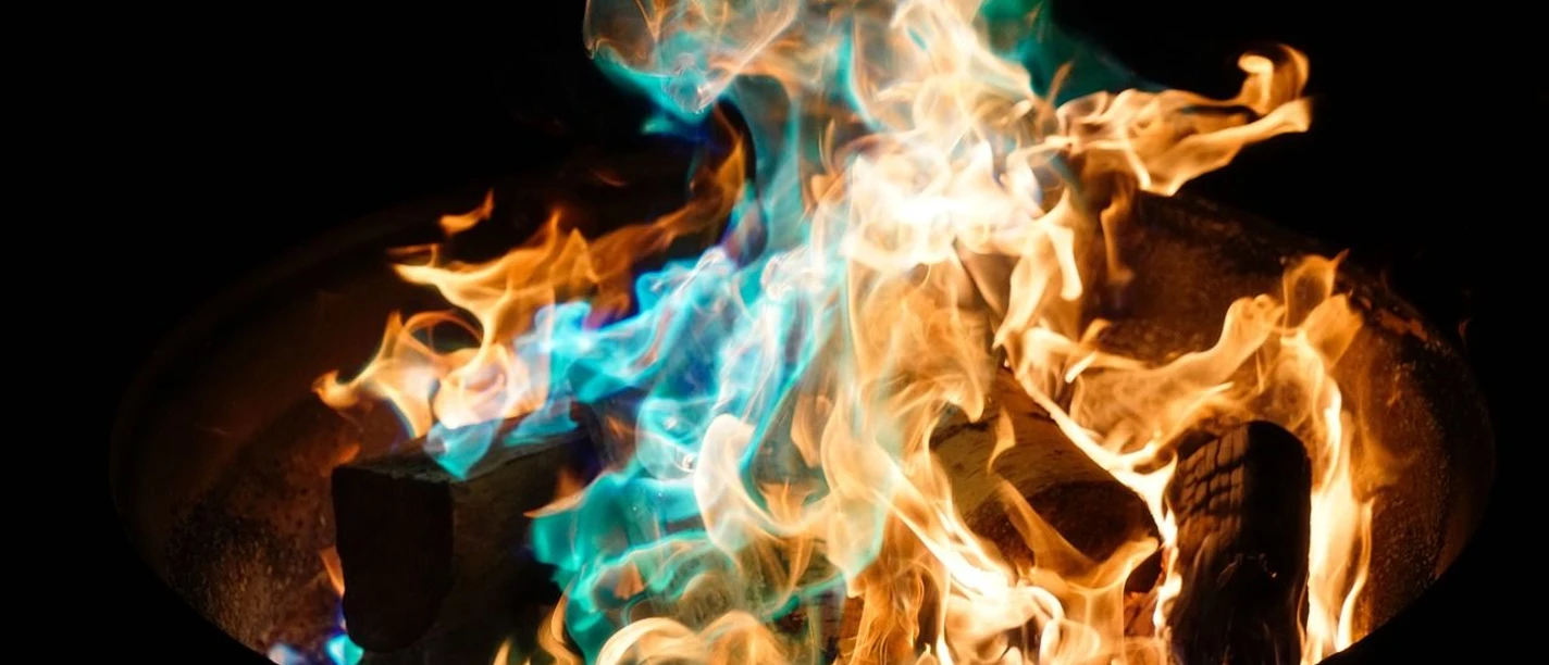 Tonnenfeuer Ein knisterndes Tonnenfeuer mit faszinierenden orange-blauen Flammen vor dunklem Hintergrund.