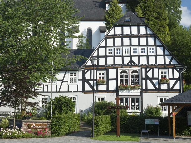 Stickereimuseum Oberhundem am Pastorsgarten Historisches Fachwerkhaus vor Grünflächen und Blumen im Pastorsgarten von Oberhundem.