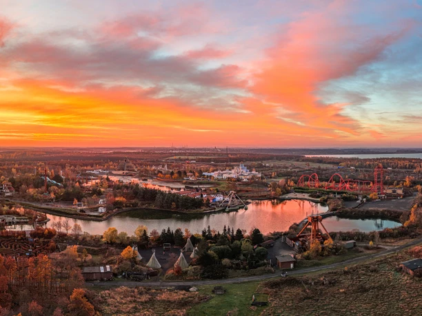 Panorama celého areálu zábavního parku BELANTIS se všemi atrakcemi při východu slunce za podzimního dne a na sousední jezera Cosupudener See a Zwenkauer See.