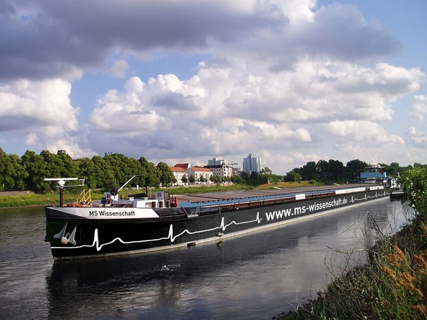 MS Science in the Science Year 2026 Exhibition ship MS Wissenschaft glides across the river against a cloudy sky.