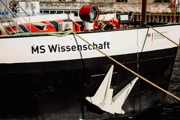 A floating science center Bow of the MS Wissenschaft with white anchor, ropes and technical equipment on deck.