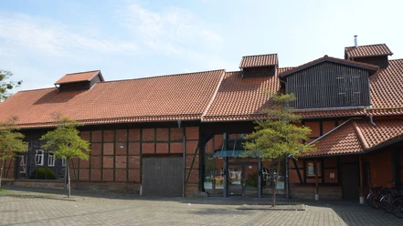 Kulturscheune_HD_16zu9.JPG Backstein-Fachwerkscheune mit rotem Ziegeldach, Glaseingang und Vorplatz.