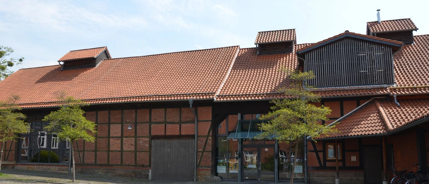 Kulturscheune_HD_16zu9.JPG Backstein-Fachwerkscheune mit rotem Ziegeldach, Glaseingang und Vorplatz.