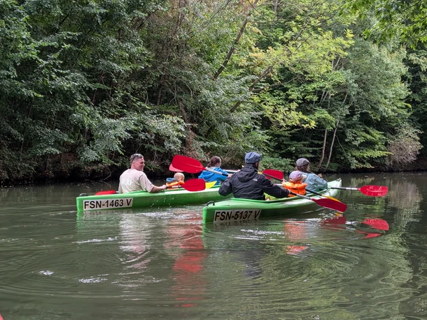 Bootsverleih am Klingerweg - Wasserwandern in Leipzig Mit Paddeln in der Hand fahren zwei Familien in zwei Kanus auf den Gewässern Leipzigs durch die grüne Landschaft