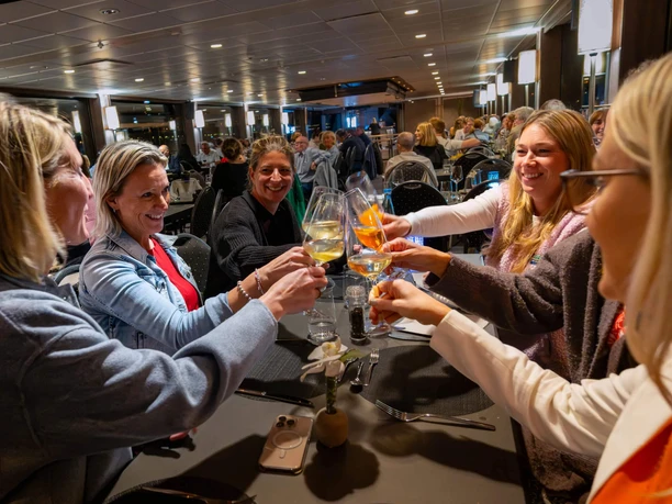 Evening event Group raises glasses at a festively laid table in a lively ship restaurant.