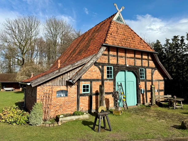 Historisches Fachwerkhaus aus rotem Backstein mit grünem Holztor unter blauem Himmel in Langwedel.