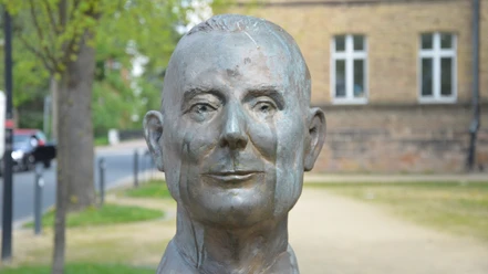 Franz Zobel_HD_16zu9.JPG Bronzene Büste von Franz Zobel im Freien vor unscharfen Bäumen und einem Haus.