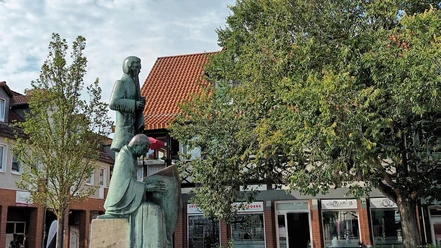 Klesmer_HD_16zu9.jpg Bronzestatue zweier Klesmermusikanten auf einem Steinsockel vor Baum und Fachwerkhaus.