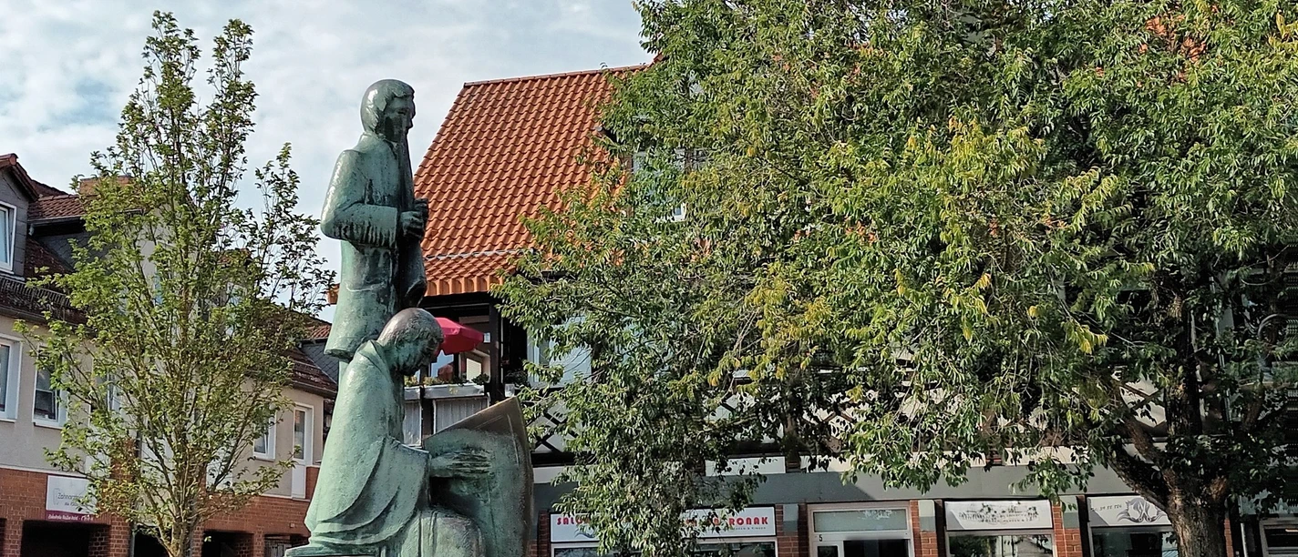 Klesmer_HD_16zu9.jpg Bronzestatue zweier Klesmermusikanten auf einem Steinsockel vor Baum und Fachwerkhaus.