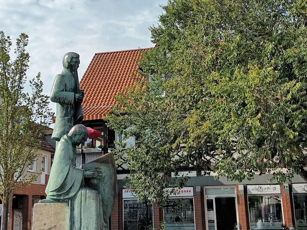 Klesmer_HD_16zu9.jpg Bronzestatue zweier Klesmermusikanten auf einem Steinsockel vor Baum und Fachwerkhaus.