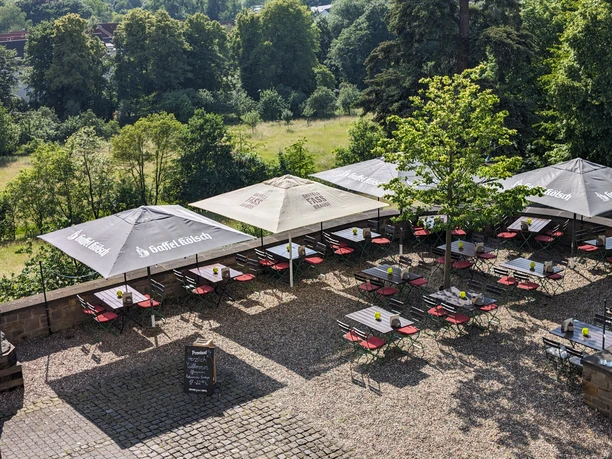 Biergarten am Kardinal-Schulte-Haus mit Sonnenschirmen, Tischen und Blick ins Grüne