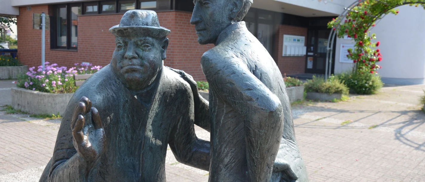 Salzsieder_HD_16zu9.jpg Zwei Bronzestatuen der Salzsieder im lebhaften Gespräch auf einem bepflanzten Vorplatz.