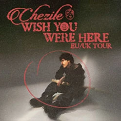 Sitzende Person im dunklen Raum, umgeben von rotem Tour-Schriftzug Wish You Were Here.