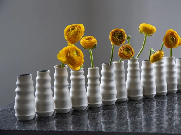 Porzellanvasen von Sandra Nitz Reihe weißer Porzellanvasen mit gelben Blüten auf dunkler Steinfläche