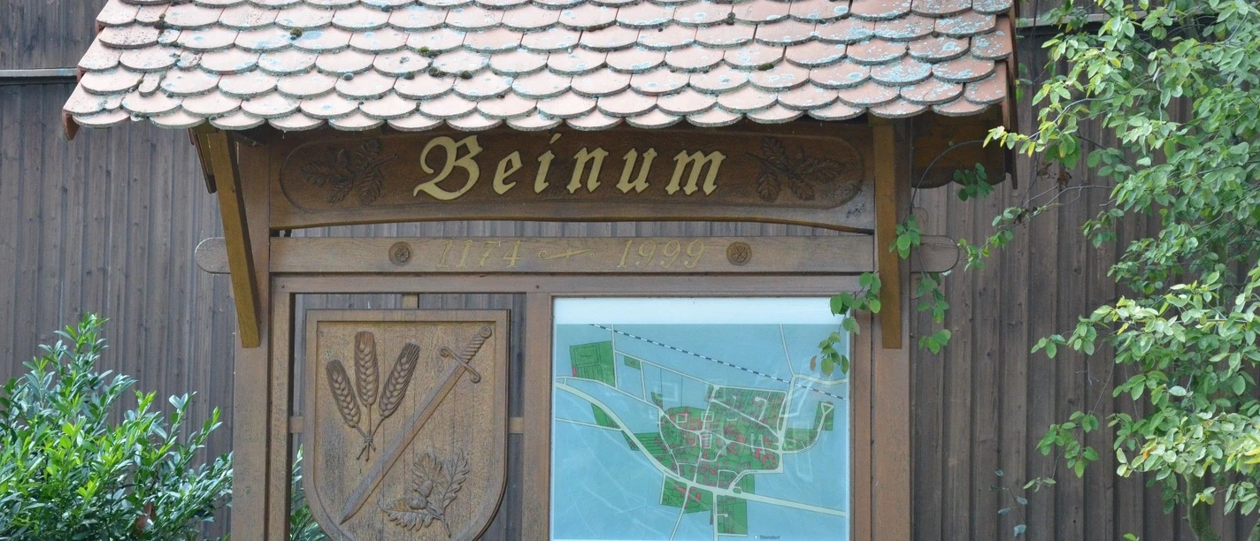 Dorftafel_Beinum_HD_16zu9.JPG Hölzerne Dorftafel Beinum mit Wappen und Ortskarte unter einem Ziegeldach.