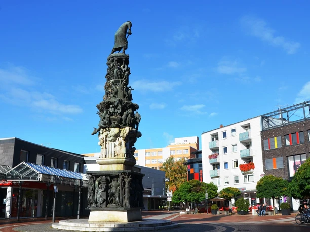 Monument_zur_Stadtgeschichte_Salzgitter_HD_16zu9.JPG Hohes Stadtmonument Salzgitter mit vielen Figuren auf einem städtischen Platz.
