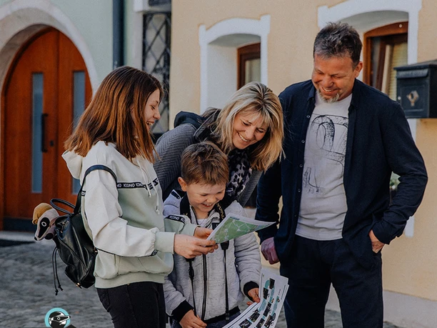Detektiv-Trails-Familie (c) MyCityHighlight Europe GmbH.jpg Eine lachende Familie betrachtet gemeinsam eine Karte auf dem Detektiv-Trail.