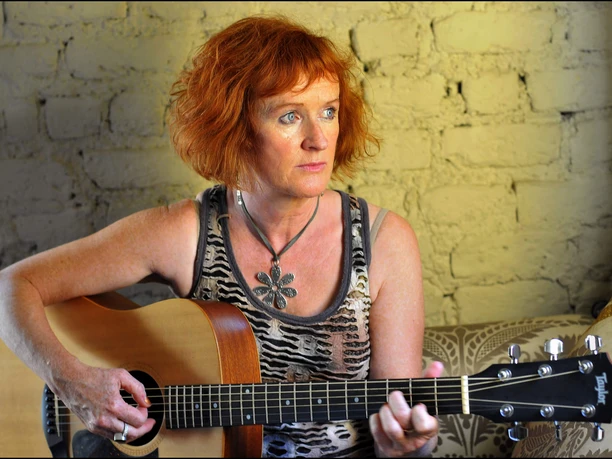 Rosena Horan-(c) Rosena Horan.jpg Irische Musikerin Rosena Horan mit Gitarre vor Steinwand