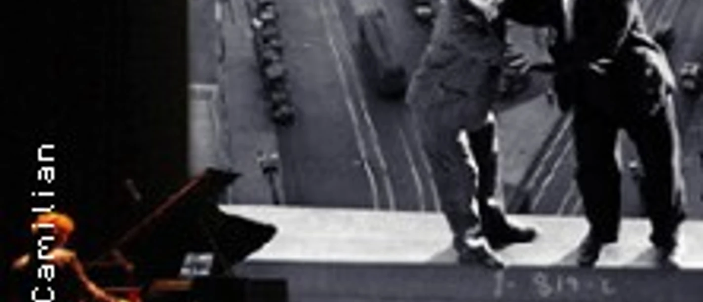 Pianist vor großer Leinwand mit Schwarzweißszene zweier Männer auf hoher Stahlkante.