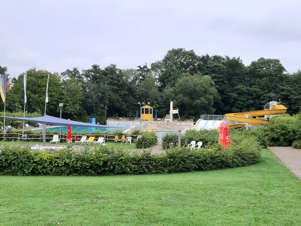 Sport- und Abenteuerbecken mit Kinderbereich Außenbecken mit gelber Rutsche, Kinderbereich, Liegewiesen und Sonnensegeln