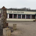CJD Hallendorf_HD_16zu9.JPG Flaches Gebäude des CJD Salzgitter mit gepflastertem Vorplatz und verzierten Steinsäulen.