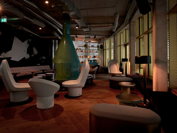 Monkey Bar Modern beleuchtete Lounge mit runden Sitzmöbeln, großem Kamin und breiten Fensterfronten