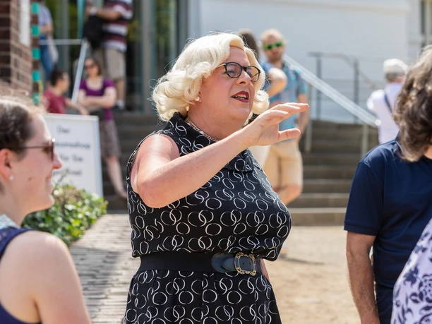 Stadtrundgang mit Aurora DeMeehl Aurora DeMeehl mit blondierter Lockenperücke,