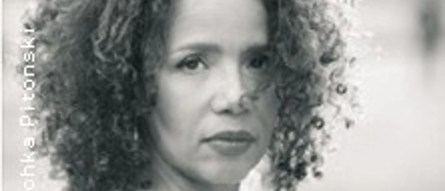 Porträt einer Frau mit lockigem Haar im Freien, frontal blickend in sanftem Licht