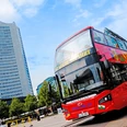 Original Leipziger Stadtrundfahrten - Erlebnisse und Touren in Leipzig Auf dem Augustusplatz steht ein roter Doppeldeckerbus der Original Leipziger Stadtrundfahrten, im Hintergrund ist das City-Hochhaus zu sehen