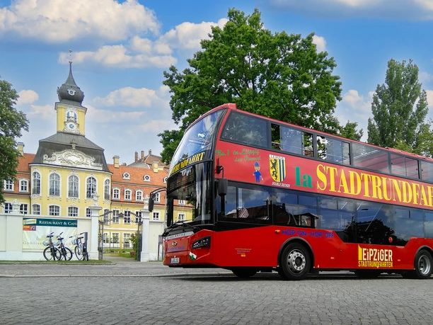 Le bus rouge à deux étages de l'Original Leipziger Stadtrundfahrten est garé devant le petit château de Gohlis.