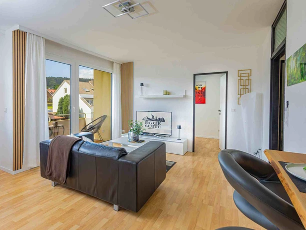 Ferienwohnung Egge Suite Helles Wohnzimmer mit Sofa, TV, Balkonzugang und moderner Einrichtung