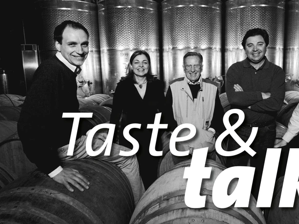 Taste & Talk im Kölner Weinkeller x Livio-Felluga Gruppe vor Weinfässern und Edelstahltanks mit großem Taste & talk Schriftzug.