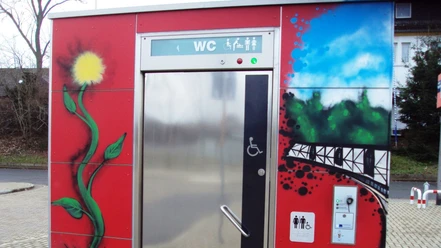 Bahnhof_Salzgitter-Ringelheim_WC-Anlage_HD_16zu9.JPG Rote, mit farbigen Graffitis bemalte öffentliche WC-Anlage. Ein Rollstuhlsymbol ziert die Tür.
