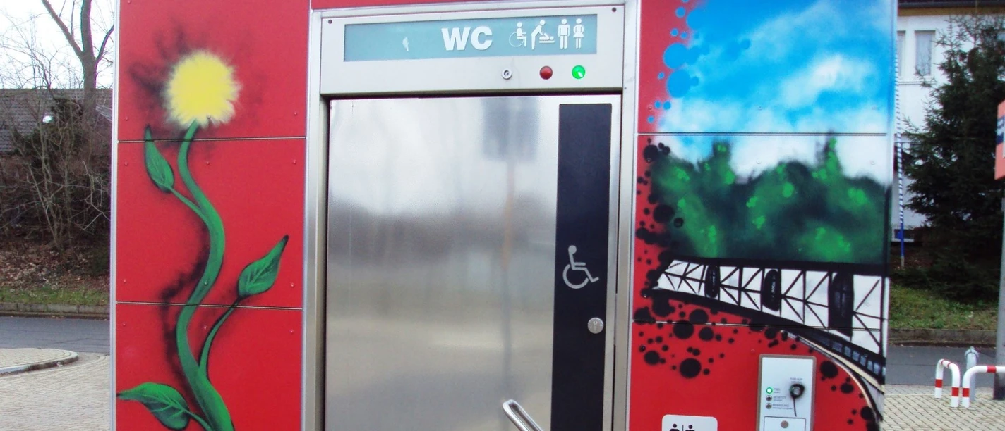 Bahnhof_Salzgitter-Ringelheim_WC-Anlage_HD_16zu9.JPG Rote, mit farbigen Graffitis bemalte öffentliche WC-Anlage. Ein Rollstuhlsymbol ziert die Tür.