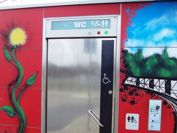 Bahnhof_Salzgitter-Ringelheim_WC-Anlage_HD_16zu9.JPG Rote, mit farbigen Graffitis bemalte öffentliche WC-Anlage. Ein Rollstuhlsymbol ziert die Tür.