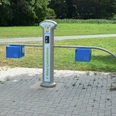 E-Bike-Ladestelle_Salzgittersee_WEVG_HD_16zu9.JPG Moderne E-Bike-Ladestation am Salzgittersee mit vier Anschlüssen auf gepflasterter Fläche im Grünen.