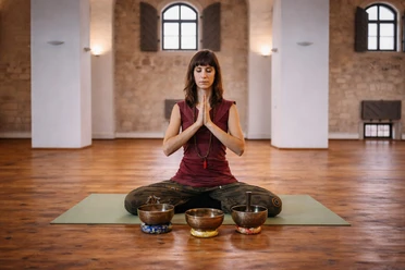 Eine Frau sitzt in Meditationshaltung auf dem Boden