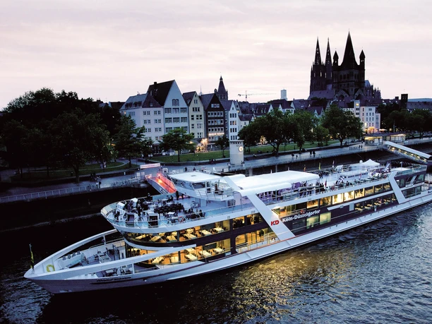 All-inclusive Abendfahrt Köln Abendliche Rheinpassage mit modernem Fahrgastschiff vor Kölns historischer Altstadtkulisse