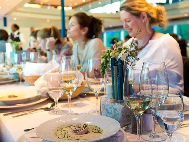 All-inclusive evening trip to Cologne Festively laid table with food, glasses and guests during an evening cruise
